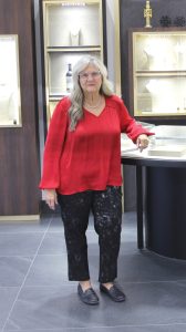 Woman in red shirt and black pants standing in a jewelry store